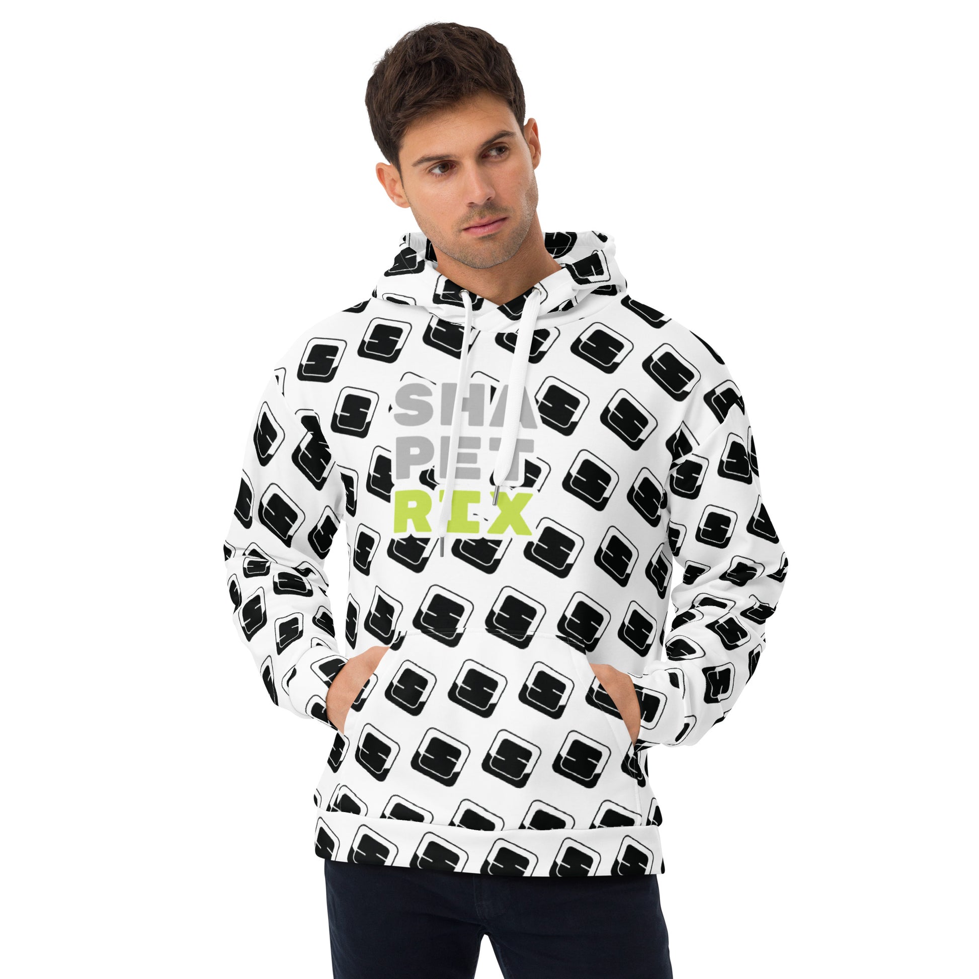 This image features a Caucasian man wearing a white hoodie adorned with an all-over black pattern of the stylized Shapetrix 'S' logo. The brand name "SHAPETRIX" is displayed prominently in lime green across the chest. He stands with his hands in his pockets, looking directly at the camera with a calm expression. The hoodie features a drawstring hood and a relaxed fit, emphasizing a casual yet fashionable look suitable for various casual settings.