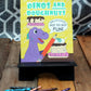 A colorful photo showcasing the "Dinos and Doughnuts" dot-to-dot activity book displayed on a black stand. The cover features a cheerful purple dinosaur holding a giant pencil next to a stack of doughnuts with vibrant icing and sprinkles. The text reads "Delicious Dot to Dot Fun!" against a bright yellow background patterned with doughnuts and the word "YUM." Crayons in various colors are scattered on the wooden surface below, adding a creative and playful vibe to the scene.