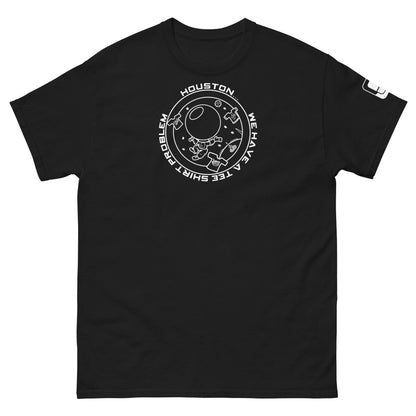 A sleek black t-shirt featuring a whimsical circular design that reads "Houston...we have a tee shirt problem," showcasing a floating astronaut and whimsical elements like floating t-shirts and a quirky UFO.