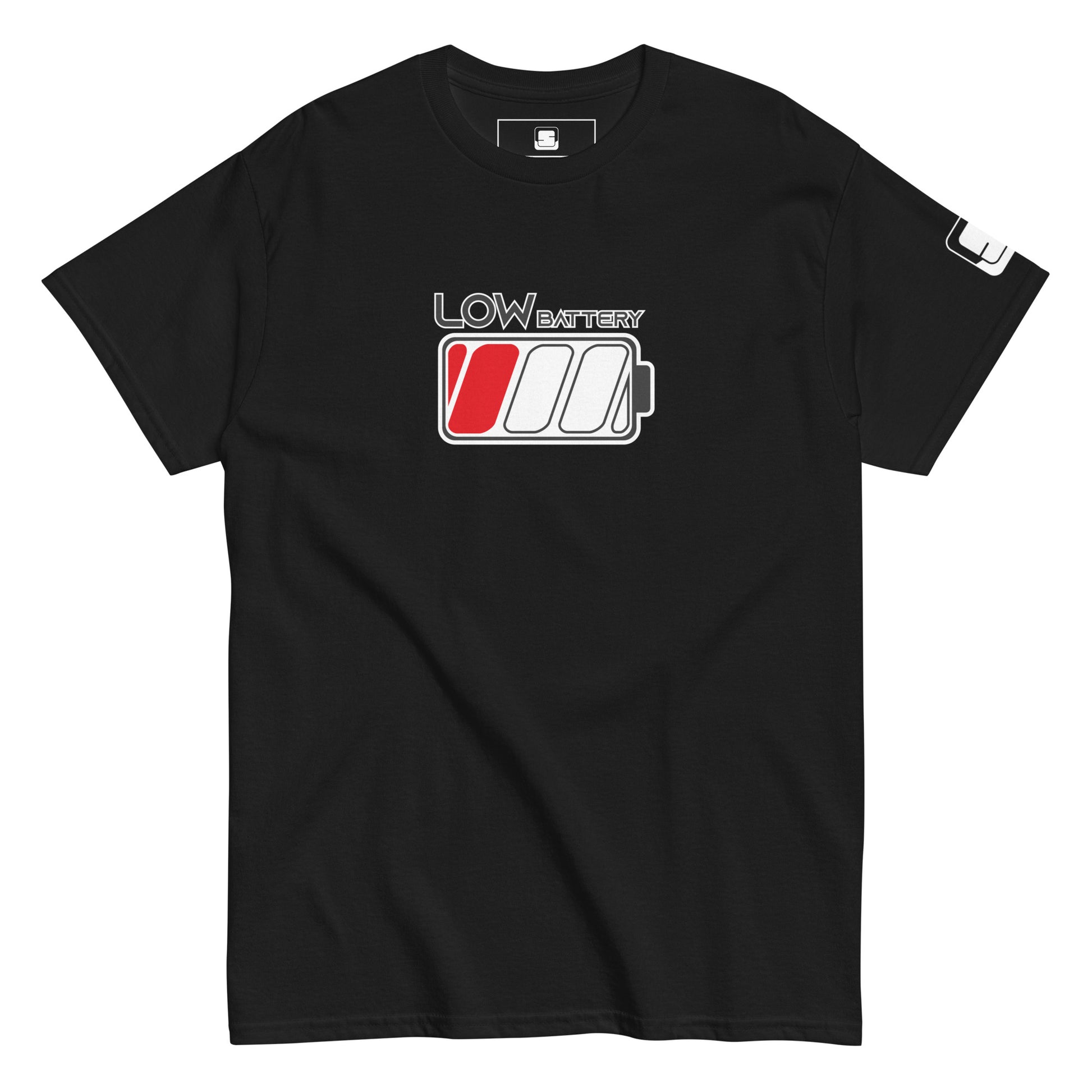 A black t-shirt displays the design "LOW BATTERY" in grey lettering with a white outline on the upper chest area. Below the text is a stylized battery icon with three sections; the leftmost cell is filled in red to indicate a low charge. The shirt has a casual fit with a ribbed crew neckline and short sleeves, each accented by a small black logo patch on the right sleeve.
