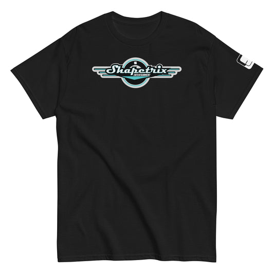 A flat-laid black t-shirt featuring the Shapetrix Entertainment logo prominently on the chest. The logo, designed with stylized white and teal lettering, is framed by a black circular backdrop with wing-like extensions on either side, creating a dynamic, retro-modern look. The left sleeve of the shirt displays a small, rectangular tag with the Shapetrix Entertainment logo, adding an additional branding detail to the garment's sleek and casual design.