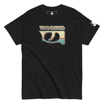 A close-up view of a black t-shirt featuring a vibrant, retro-inspired graphic. The design highlights a colorful gun trigger with the word 'TRIGGERED' across the top. 