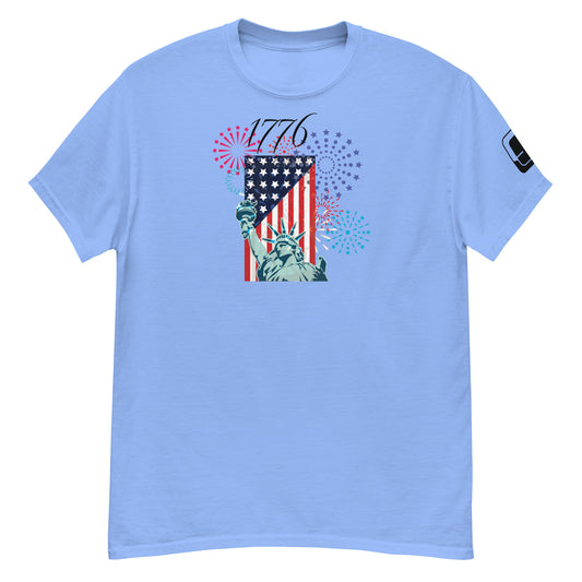 A light blue t-shirt featuring a festive graphic celebrating American independence. The design includes the iconic Statue of Liberty and a stylized U.S. flag, complemented by an array of fireworks in red, white, and blue. The year '1776' is prominently displayed, adding a historical touch to the modern style.