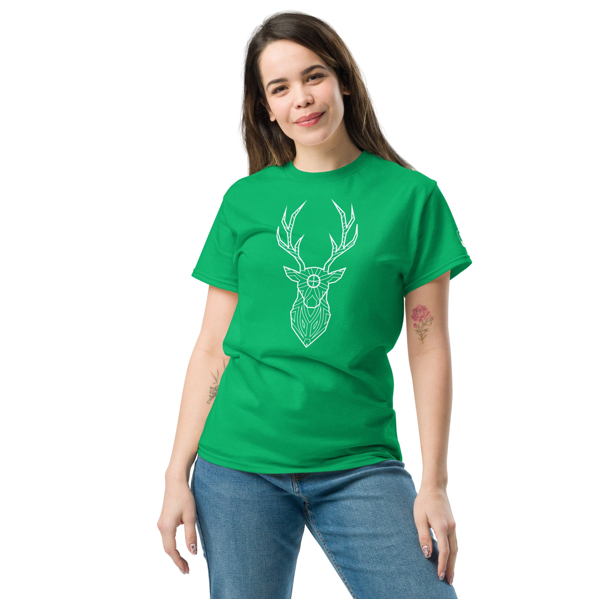 A Caucasian woman casually poses in a Irish green t-shirt adorned with a white, geometric deer head design, paired with light denim jeans.