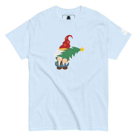 Light blue t-shirt featuring a colorful design of a gnome in a red hat decorated with yellow snowflakes, holding a green Christmas tree topped with a yellow star. The gnome is whimsically drawn with oversized white beard and tiny feet peeking out under a blue coat with golden snowflake details.