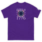 A vibrant purple t-shirt displayed flat, featuring a patriotic "July 4, 1776" graphic design in white. The design includes a motif of the American flag with red and white stripes and a blue field of white stars arranged in a circular pattern to evoke a celebratory firework. The design is both eye-catching and symbolic, celebrating American independence and ideal for Fourth of July festivities.