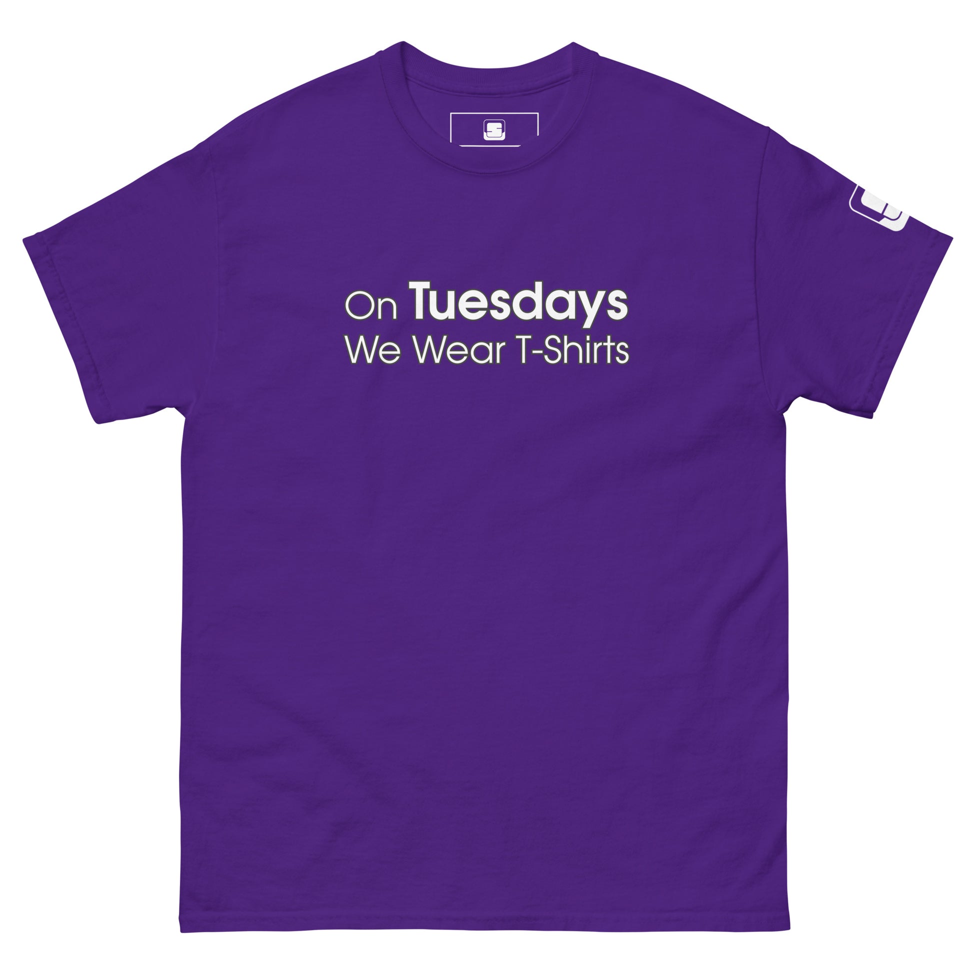 A vivid purple t-shirt displayed flat with the playful phrase "On Tuesdays We Wear T-Shirts" printed in white uppercase letters across the chest. The shirt has a classic crew neckline and short sleeves, featuring a small logo patch on the left sleeve, adding a subtle branded touch to the simple yet statement-making design.