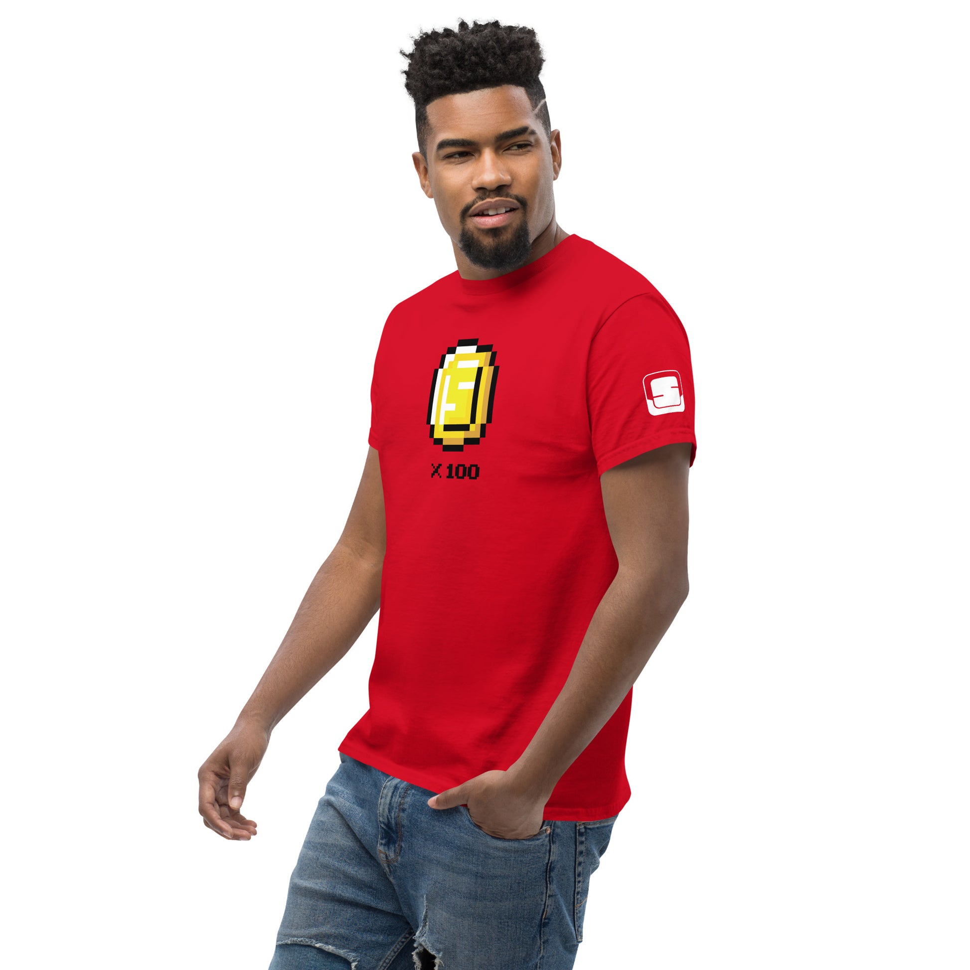 A stylish young African American man sports a vibrant red t-shirt featuring a l pixel art style design of a golden coin with the letter 'S' and the multiplier "x 100" displayed on the front. His confident stance, coupled with a casual lean, pairs well with his light-wash denim jeans. enhancing his trendy and approachable look. The simplicity of the design on the shirt stands out against the bold red background, making it a striking fashion statement.