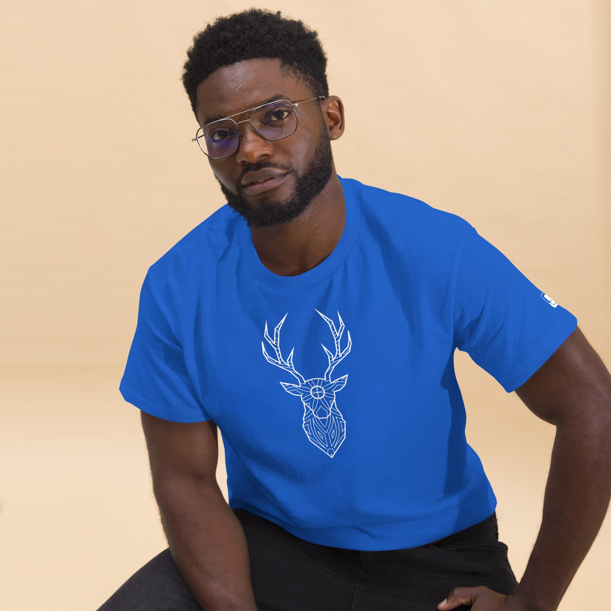 An African American man looking stylish in a royal blue t-shirt that features a white geometric deer design, complementing his casual look