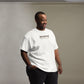 Man chuckling to himself, clad in a casual white t-shirt with the quirky statement 'depresso' and 'when you are out of coffee' in a straightforward font, paired with black pants and a watch, in a room with a gradient grey background.