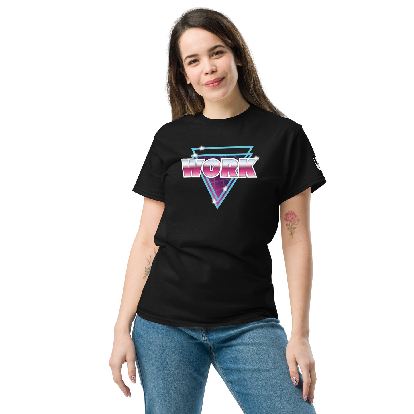 A young Caucasian woman with medium-length brown hair smiles gently while modeling a black T-shirt. The shirt features a vibrant, retro-style graphic with the word 'WORK' in large, reflective pink letters, underlined by neon blue and purple triangles. This 80s-inspired design is accented with white starbursts, giving it a dynamic and eye-catching appearance. She stands casually, against a plain background.