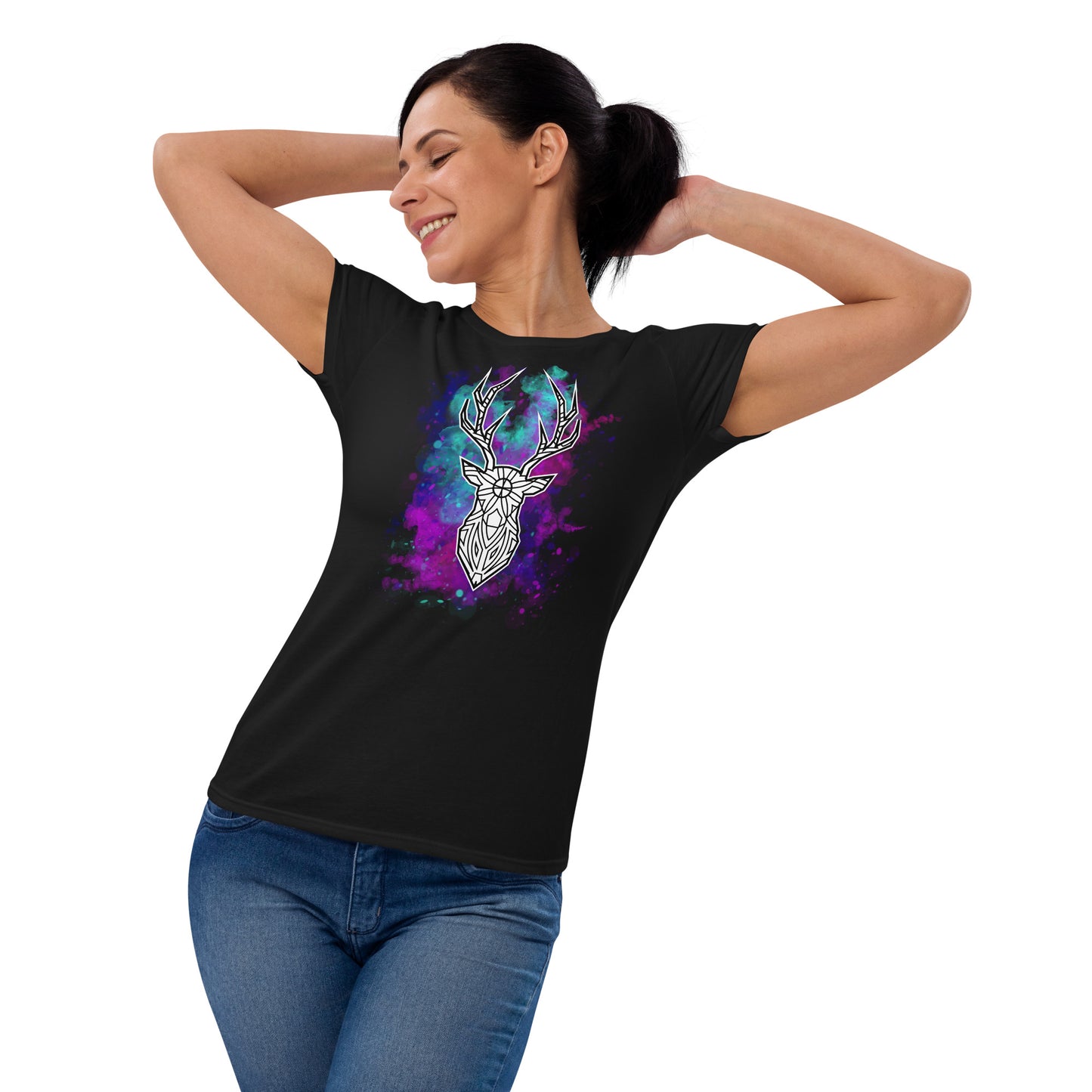 A middle-aged woman playfully poses in a black T-shirt featuring a vibrant white geometric deer head design, set against a cosmic backdrop of purple, blue, and pink nebulae. She stands with her hands clasped behind her head, smiling and looking to the side, exuding a relaxed and joyful demeanor.