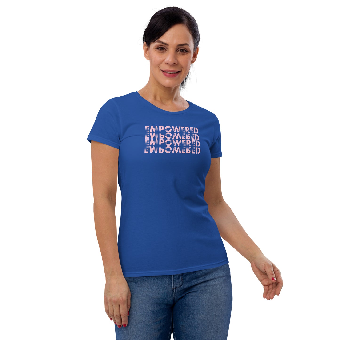 
A Caucasian woman stands confidently, modeling a vibrant blue t-shirt adorned with the word "EMPOWERED" printed four times in a staggered, overlapping layout. The text appears in a modern, slightly 3D font shaded from dark to light pink, set against the blue fabric, creating an eye-catching contrast. She poses with one hand close to her hip, her expression serene and composed, complementing the empowering message of her attire.