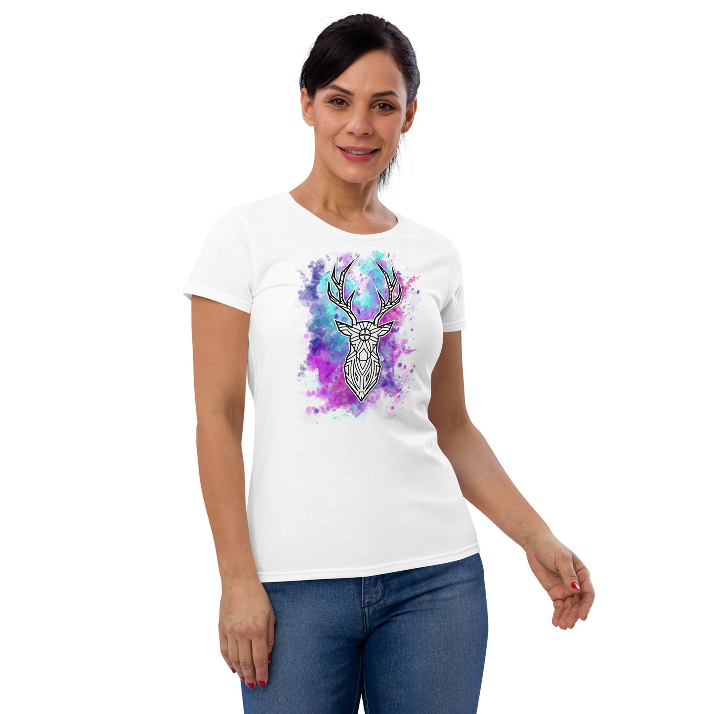 A middle-aged woman models a white T-shirt adorned with a vivid print of a geometric deer head. The design includes a splash of purple and blue watercolor-like nebula around the deer, blending artfully into the fabric. She stands relaxed with one hand slightly on her hip, smiling subtly at the camera against a plain background.