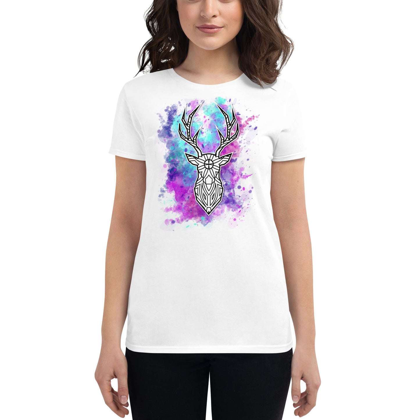 A young Caucasian woman with wavy, medium-length brown hair models a white T-shirt featuring a large, striking geometric deer head design in the center. The deer is surrounded by a vivid watercolor splash in shades of purple, blue, and pink, which gives the shirt a vibrant and artistic look. She stands with her arms at her sides, facing the camera, against a plain white background.