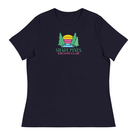 A navy blue t-shirt showcasing the "Shady Pines Escape Club" logo centered on the chest. The design features two green pine trees flanking a colorful, stylized sunset with horizontal stripes in yellow, pink, purple, and blue. Beneath the graphic, "SHADY PINES" is displayed in bold green lettering, followed by "ESCAPE CLUB" in smaller pink text. The vibrant colors of the logo stand out against the deep navy background, creating a stylish and versatile look suitable for casual occasions.